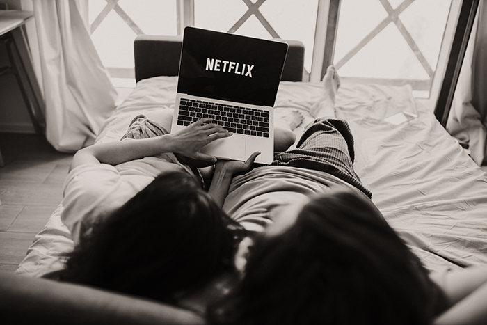 couple lounging in bed with Netflix on